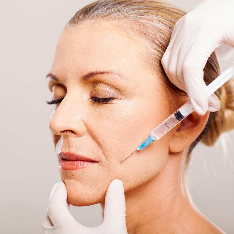 Aesthetic nurse injects filler into a woman's cheek.