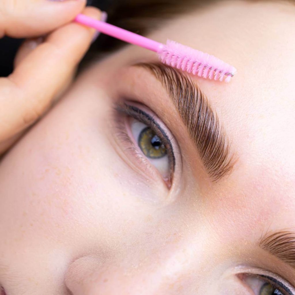 Aesthetician performs a brow lamination on client.