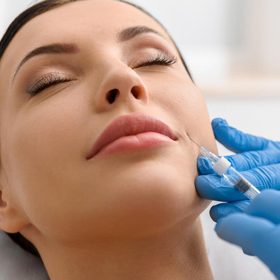 Aesthetic nurse injects filler into a woman's smile lines.