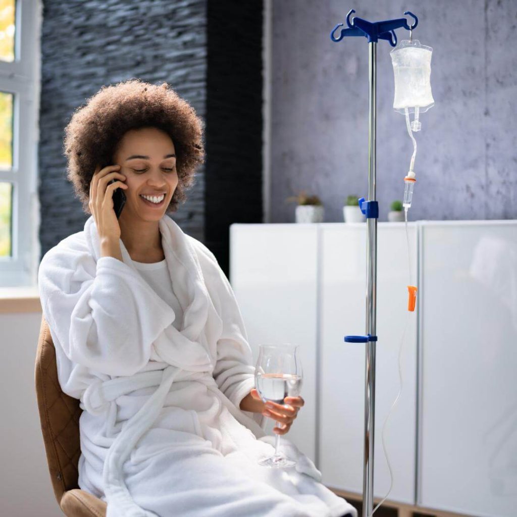 Woman talks on the phone while receiving IV drip.