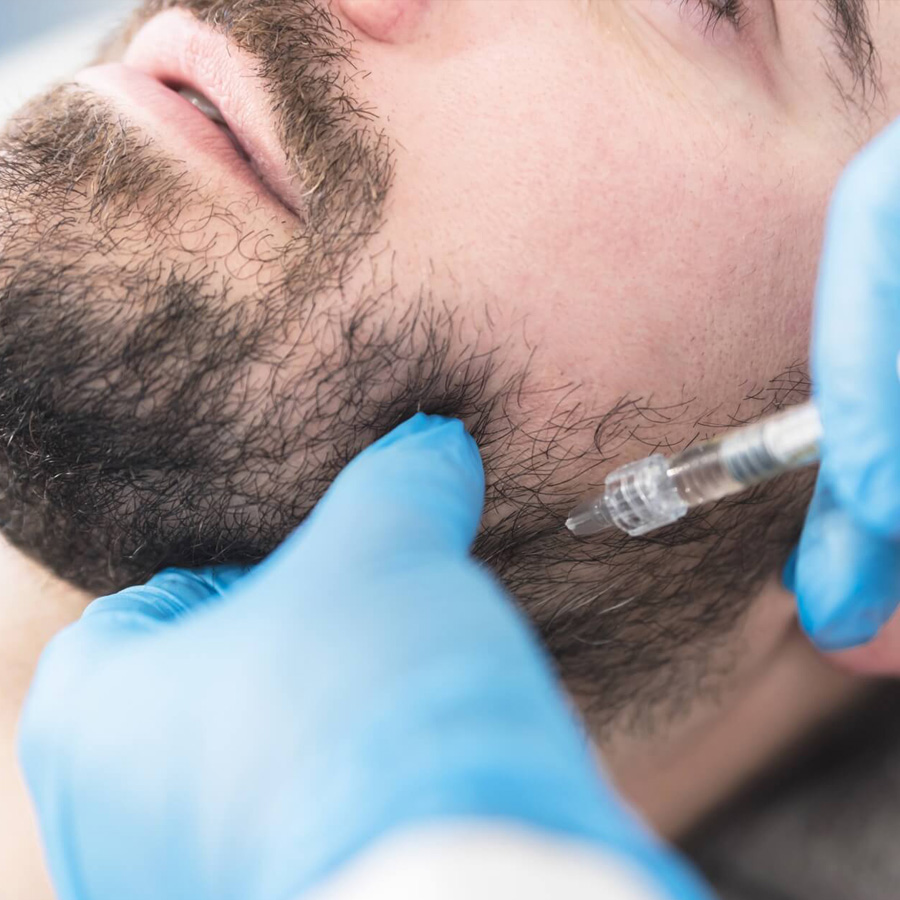 Aesthetic nurse injects filler into a man's jawline.