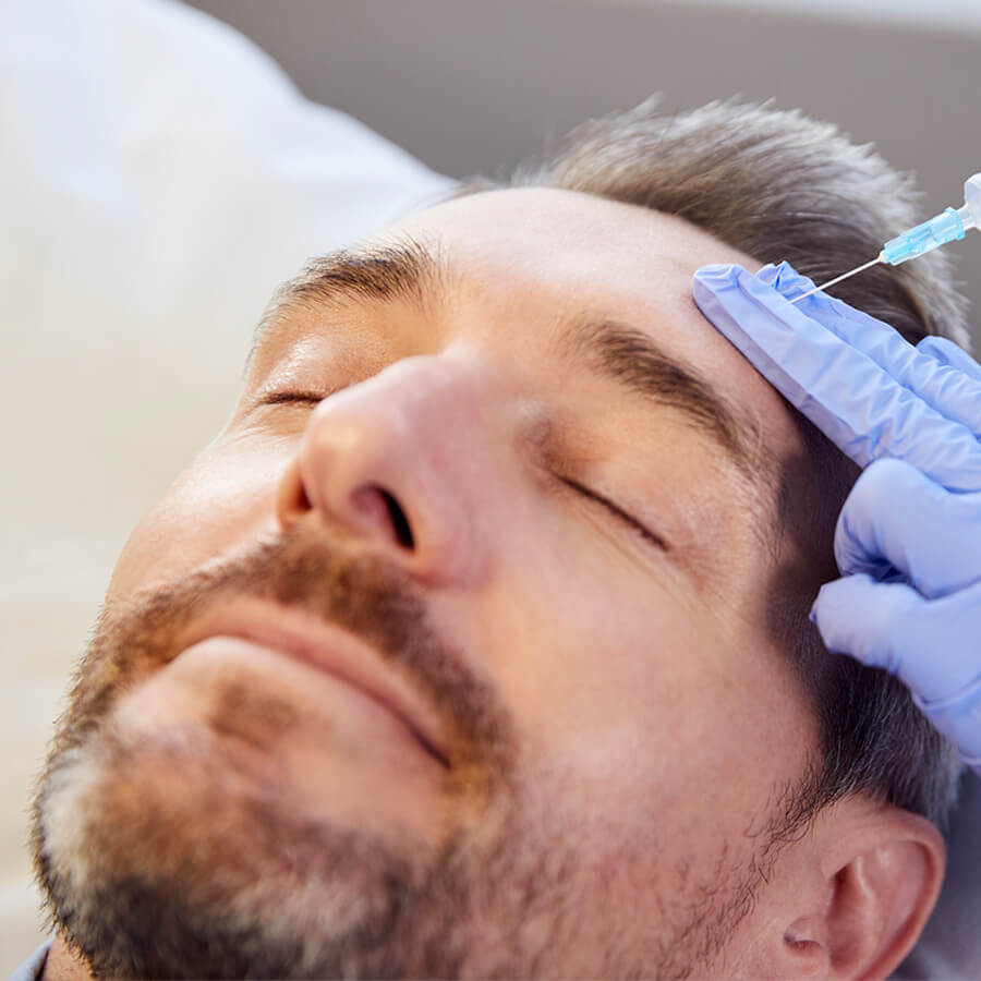 Aesthetic nurse injects botox into a man's forehead.