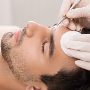Aesthetician performs extractions on a man's face.