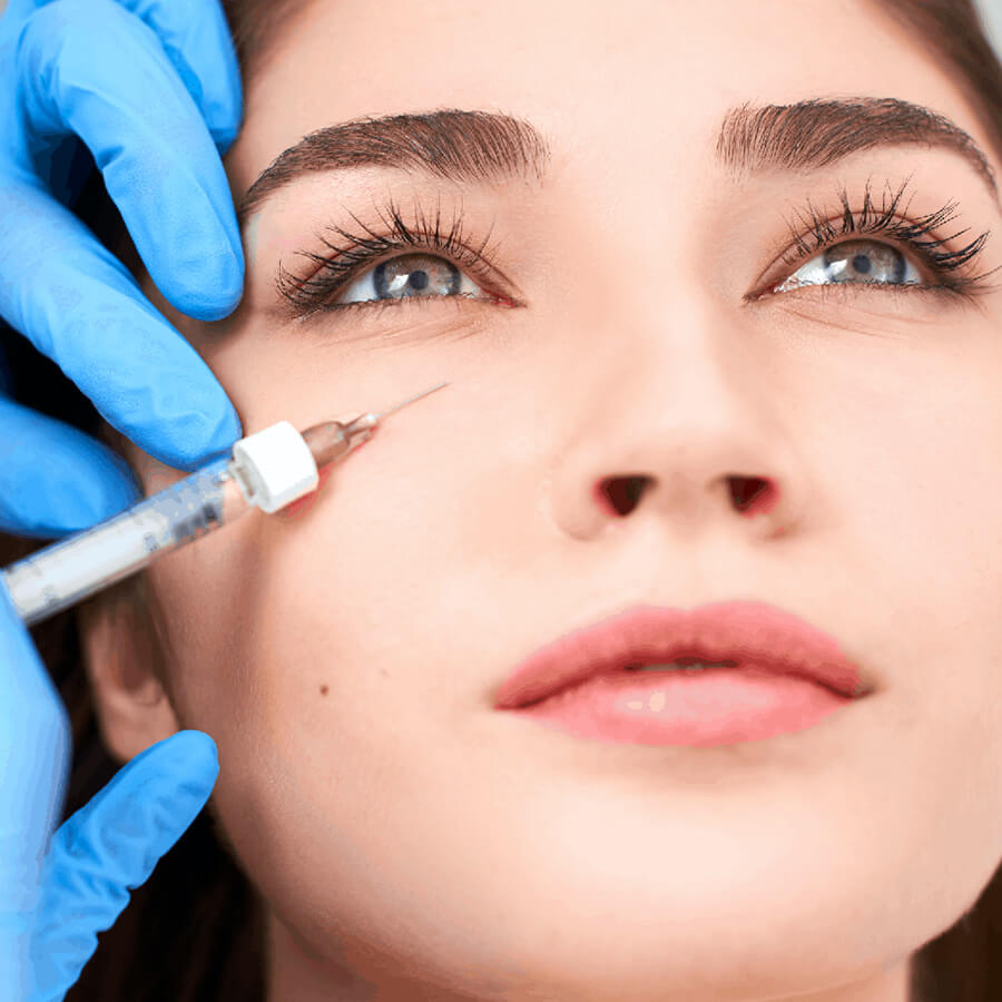 Aesthetic nurse injects filler into a woman's tear trough.